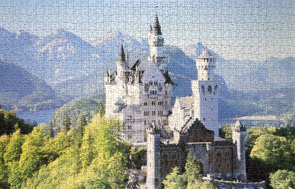 Neuschwanstein Castle nestled in a lush, mountainous landscape under a bright, clear sky.
