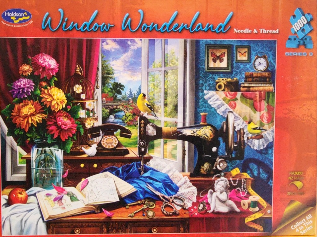 Still life of a vintage sewing table with an open book, a sewing machine, a bird, and flowers by a window.