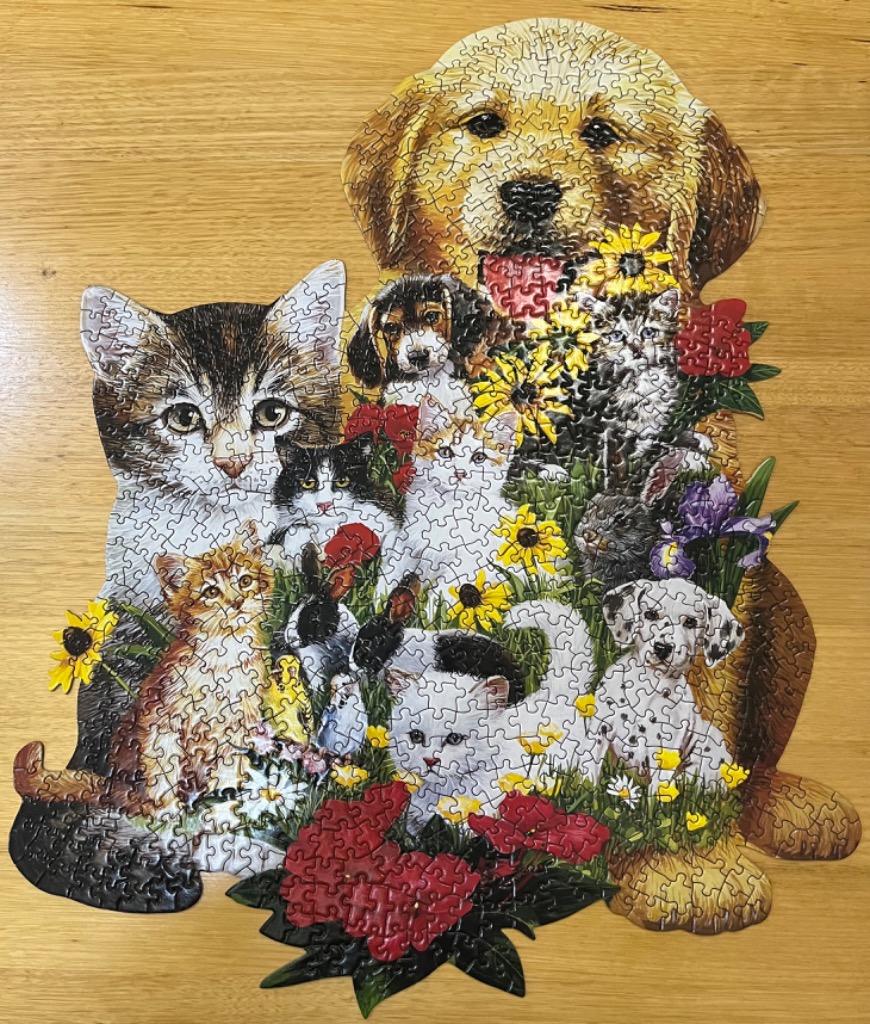 A whimsical collage of puppies, kittens, and flowers shaped like a large golden retriever.