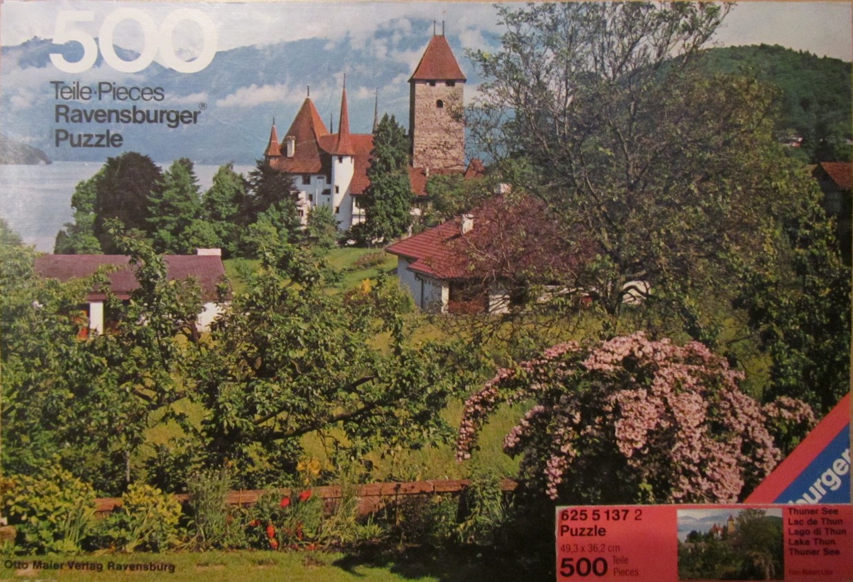 A photograph of Schadau Castle overlooking Lake Thun with a lush garden in the foreground.