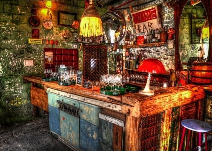A cozy, eclectic wine bar interior with rustic wooden counters and graffiti-covered walls.