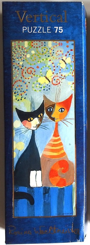 Whimsical painting of two stylized cats sitting side-by-side against a patterned blue background with butterflies.