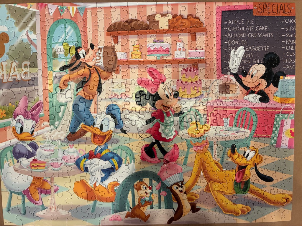 Cartoon characters Goofy, Minnie, Mickey, Donald, Daisy, Pluto, and Chip 'n Dale inside a busy bakery.