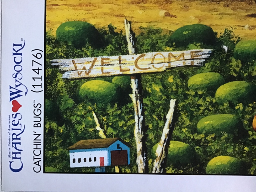 A rustic wooden sign reading WELCOME stands in a lush green watermelon patch near a small blue building.