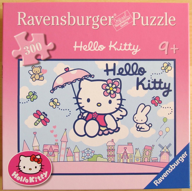 Hello Kitty floating with a pink umbrella over a fantasy town of colorful buildings and clouds.
