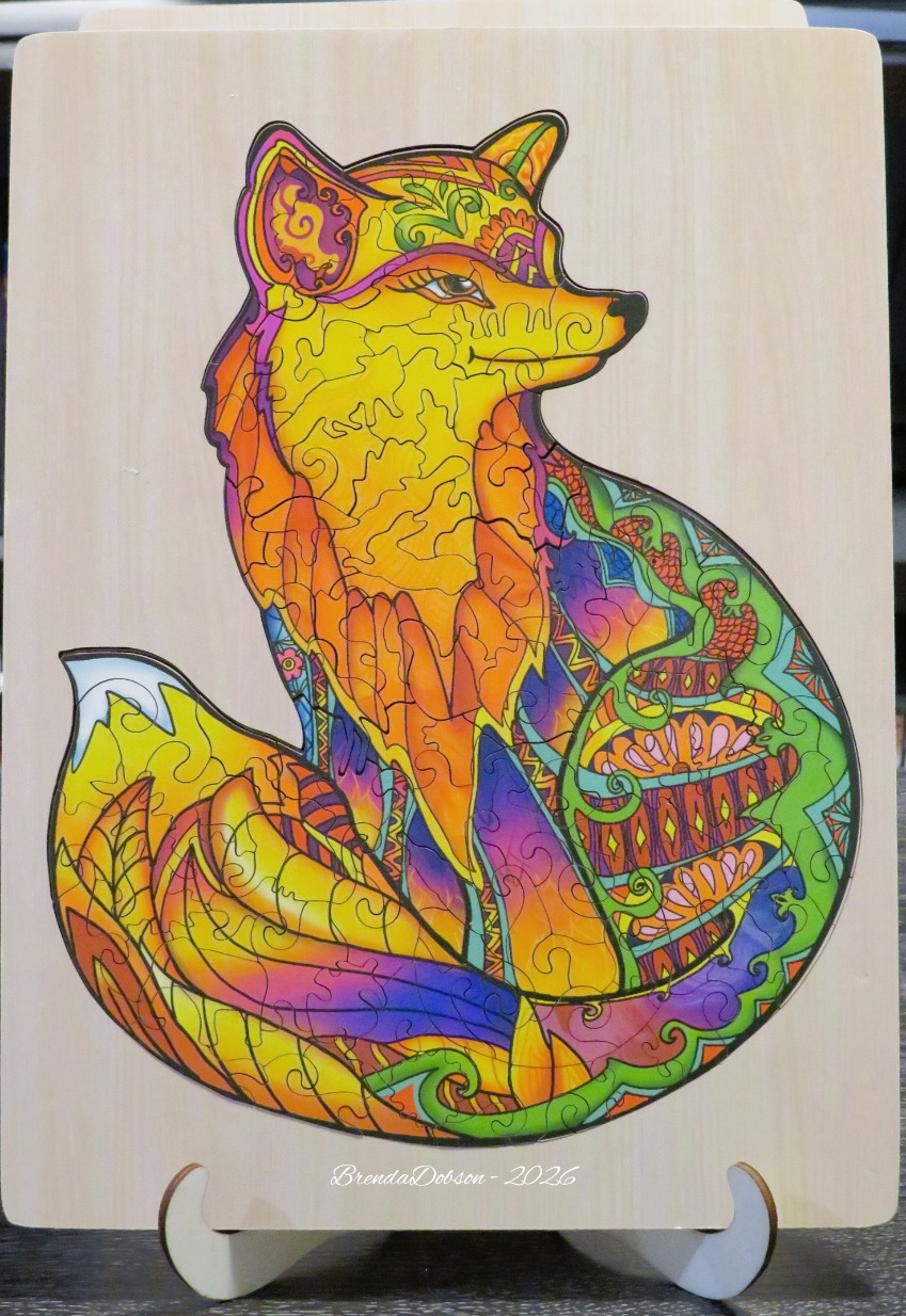 A brightly colored, stylized fox illustration with intricate patterns against a natural wood background.