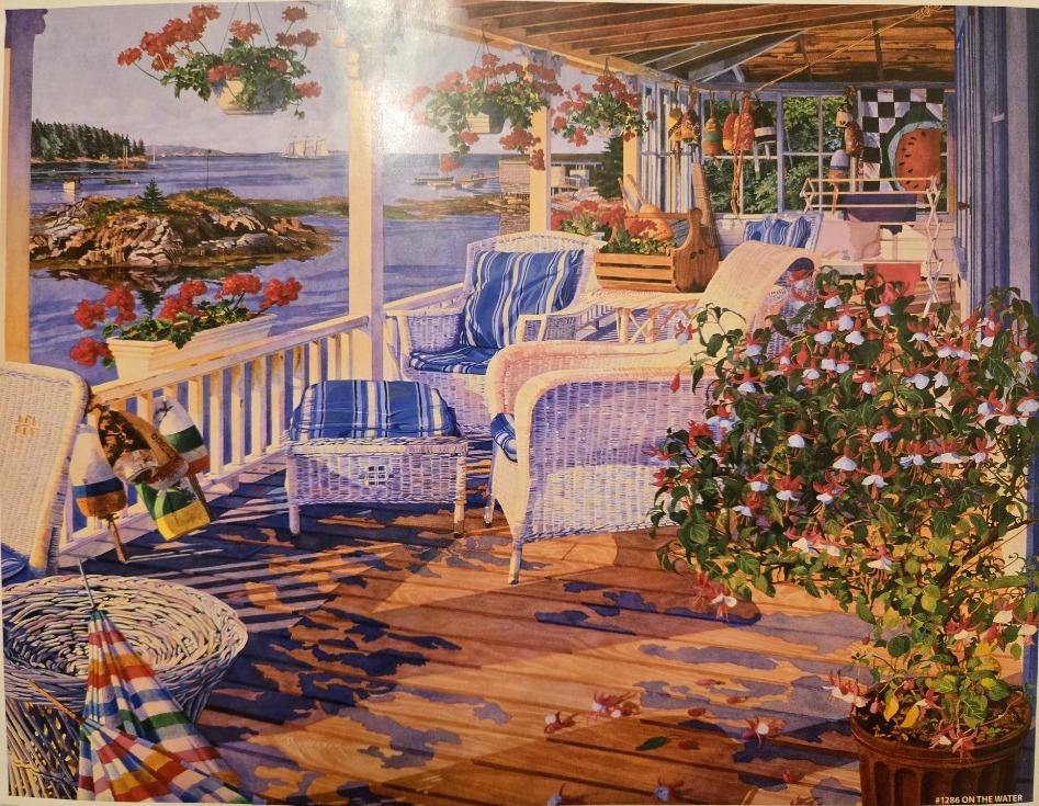 A peaceful coastal porch scene with wicker furniture, potted flowers, and a view of a calm bay with boats.