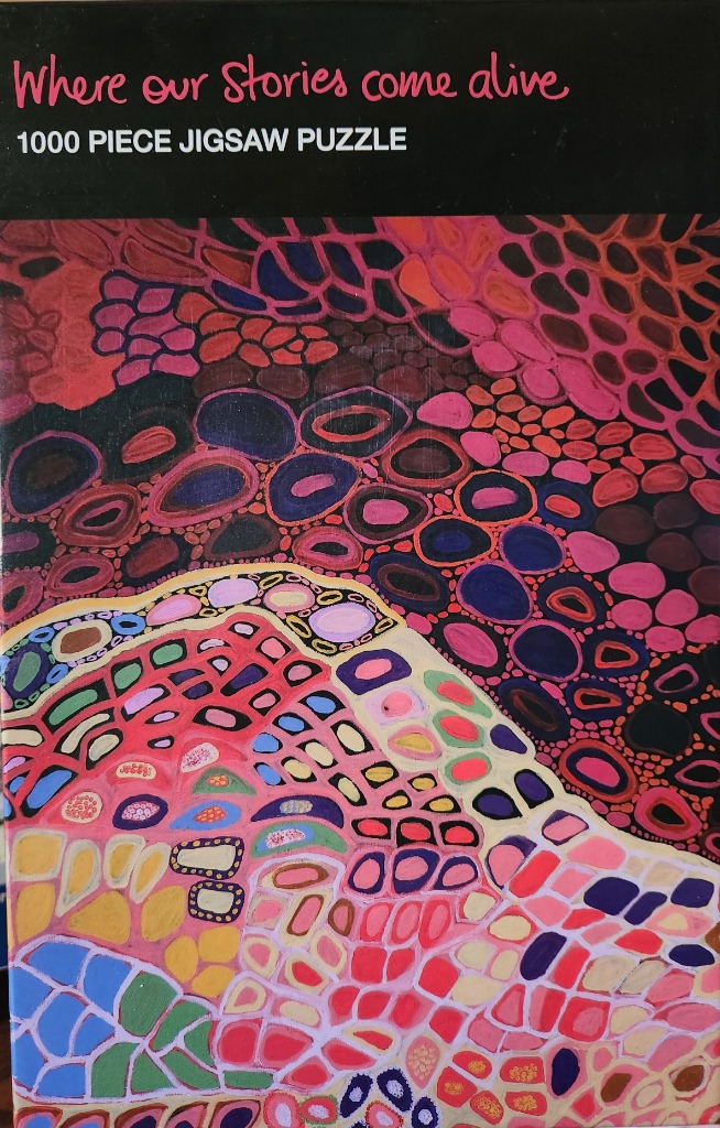 Abstract painting with cellular, organic shapes in vibrant pink, red, orange, and blue hues.