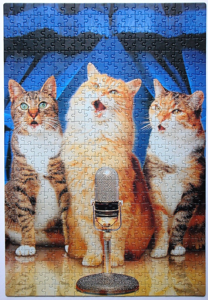 Three cats singing into a vintage microphone against a blue background