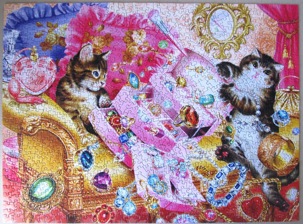 Two fluffy tabby kittens playing with an open pink jewelry box filled with sparkling gemstones and pearls.