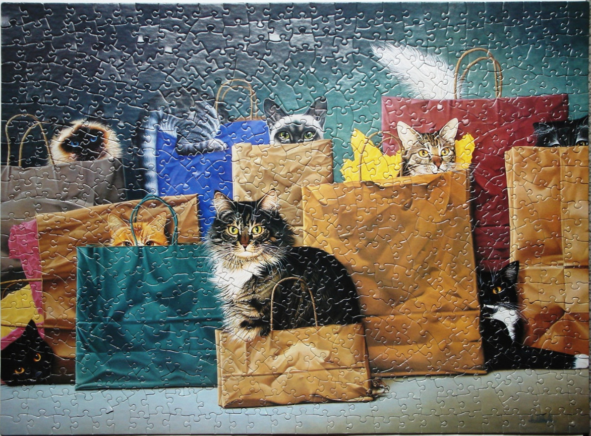 Several cats peering out from colorful paper shopping bags of various sizes and colors.
