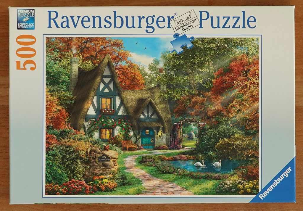 A charming thatched-roof cottage in an autumn garden with a stone path, pond, and two white swans.
