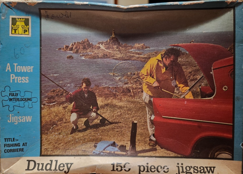 Two men preparing fishing gear by a red car overlooking a lighthouse on a rocky coastline.