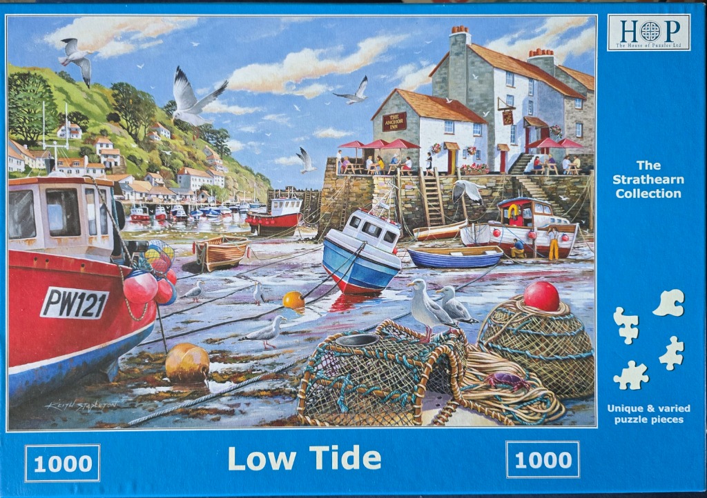 Coastal harbor scene at low tide featuring boats, a seaside inn, and seagulls.