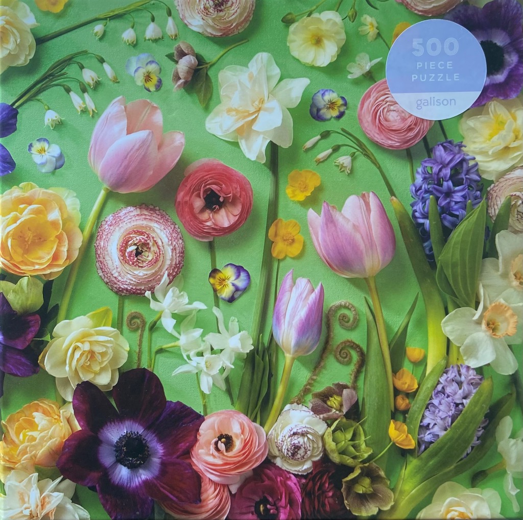 A collection of assorted spring flowers including tulips, ranunculus, and hyacinths against a vibrant green background.