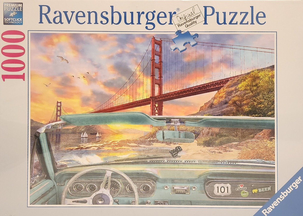 A view through the windshield of a classic convertible car looking toward the Golden Gate Bridge at sunset.
