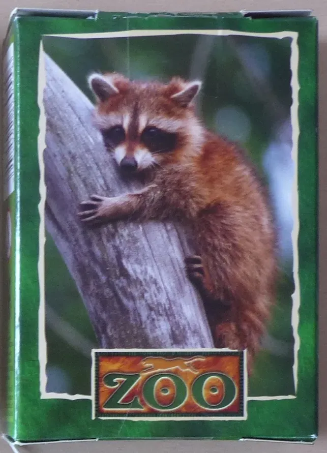 A close-up photograph of a young raccoon clinging to a tree branch against a blurred forest background.