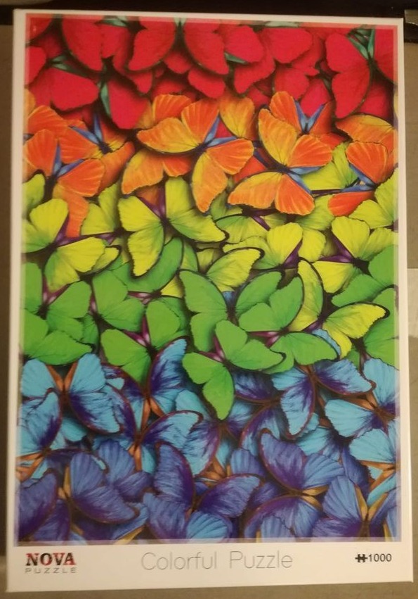 A dense arrangement of butterflies organized by color into a vibrant rainbow gradient from red to purple.