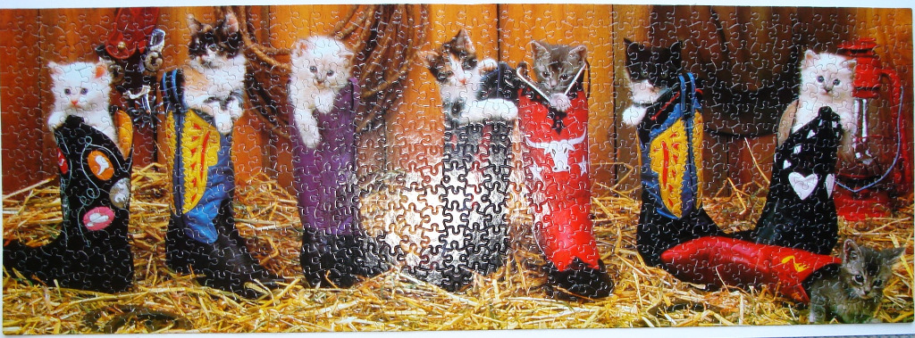 Seven kittens tucked inside colorful western-style cowboy boots sitting on a bed of straw.