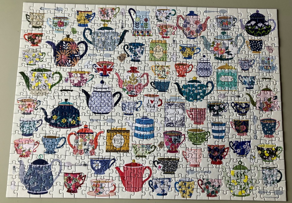 A collection of assorted teapots and teacups arranged in a pattern on a cream background.