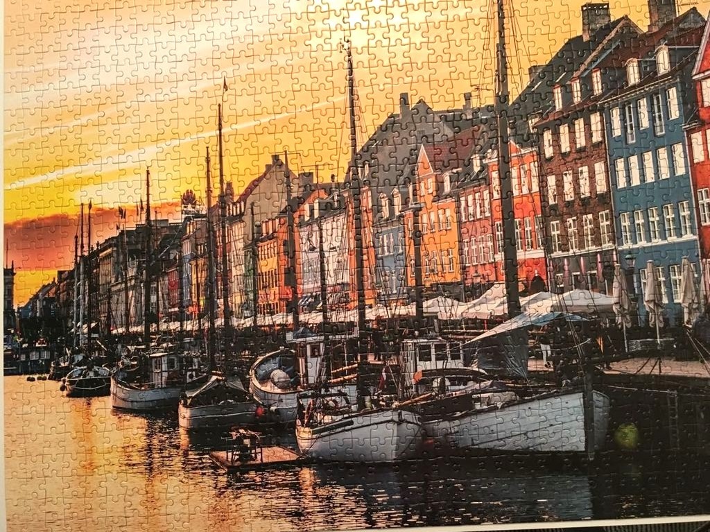 A waterfront scene with colorful canal houses and wooden boats at sunset.