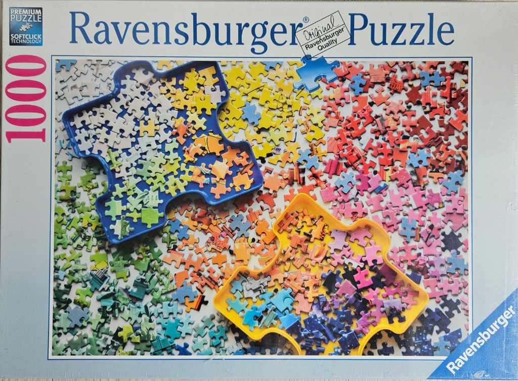 A top-down photograph showing hundreds of colorful jigsaw pieces scattered around two shaped sorting trays.