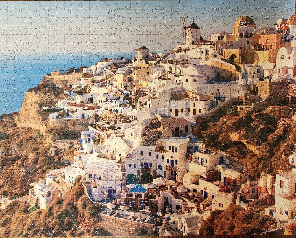 A photograph of the hillside village of Oia in Santorini, Greece, bathed in warm golden hour sunlight.