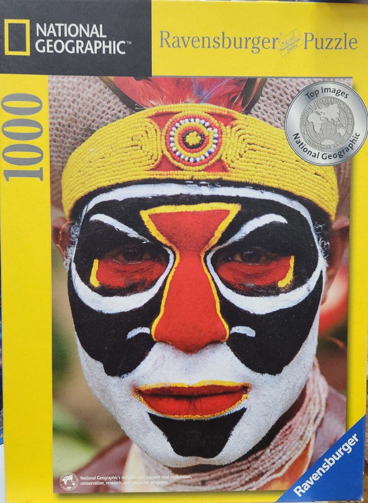 Close-up portrait of a man with elaborate traditional face paint and a beaded yellow headdress.