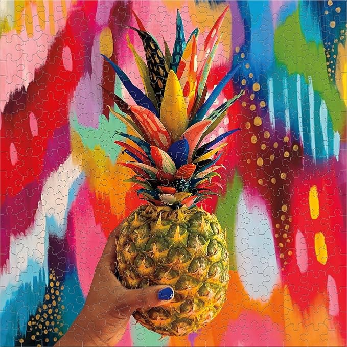 A hand holding a pineapple with multi-coloured leaves against a vibrant, abstract expressionist background.