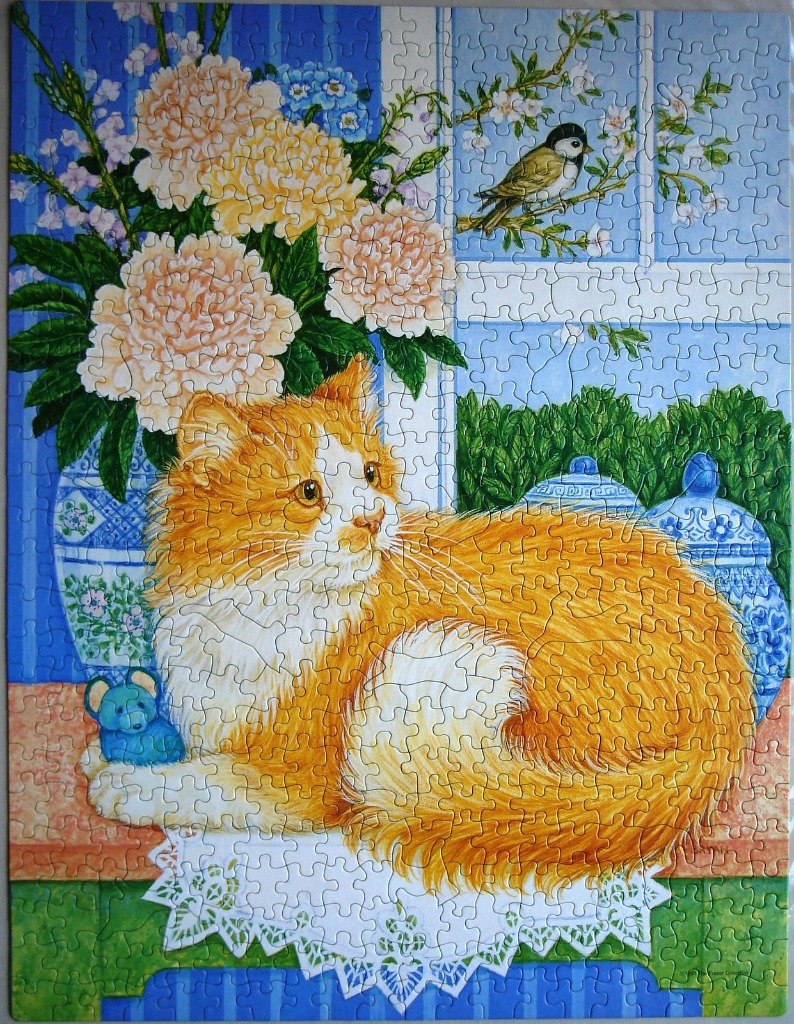 An orange and white fluffy cat sitting on a ledge next to blue pottery and a bouquet of pale pink peonies.