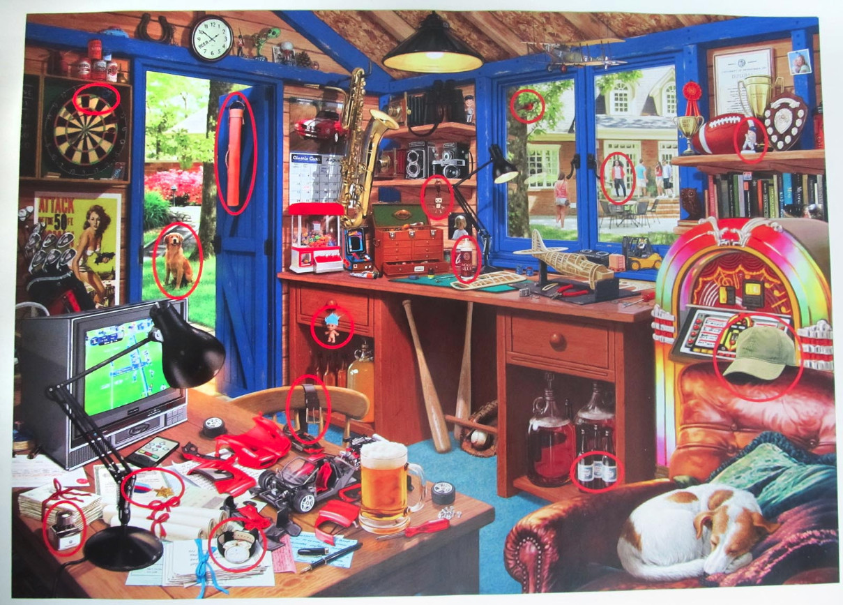 A cluttered, cozy hobby room featuring a desk with models, a jukebox, and two sleeping dogs.