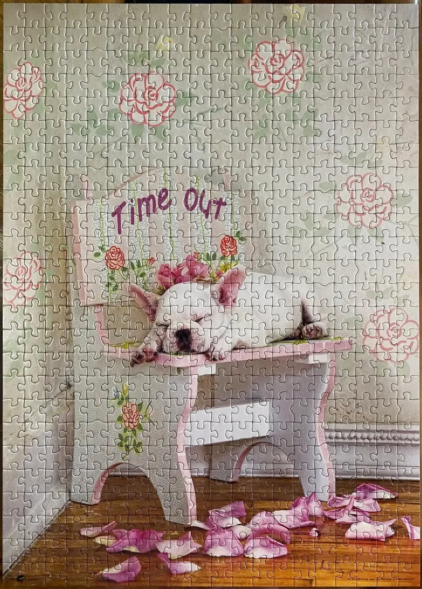 A white French bulldog puppy sleeping on a small painted wooden chair in front of a floral wallpaper background.