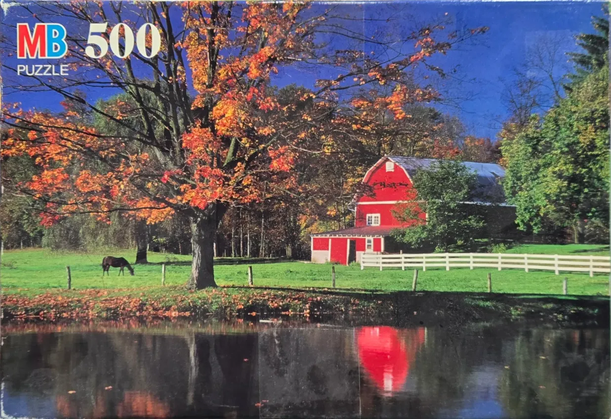 A red barn in a rural landscape with an autumn tree and a horse beside a pond.
