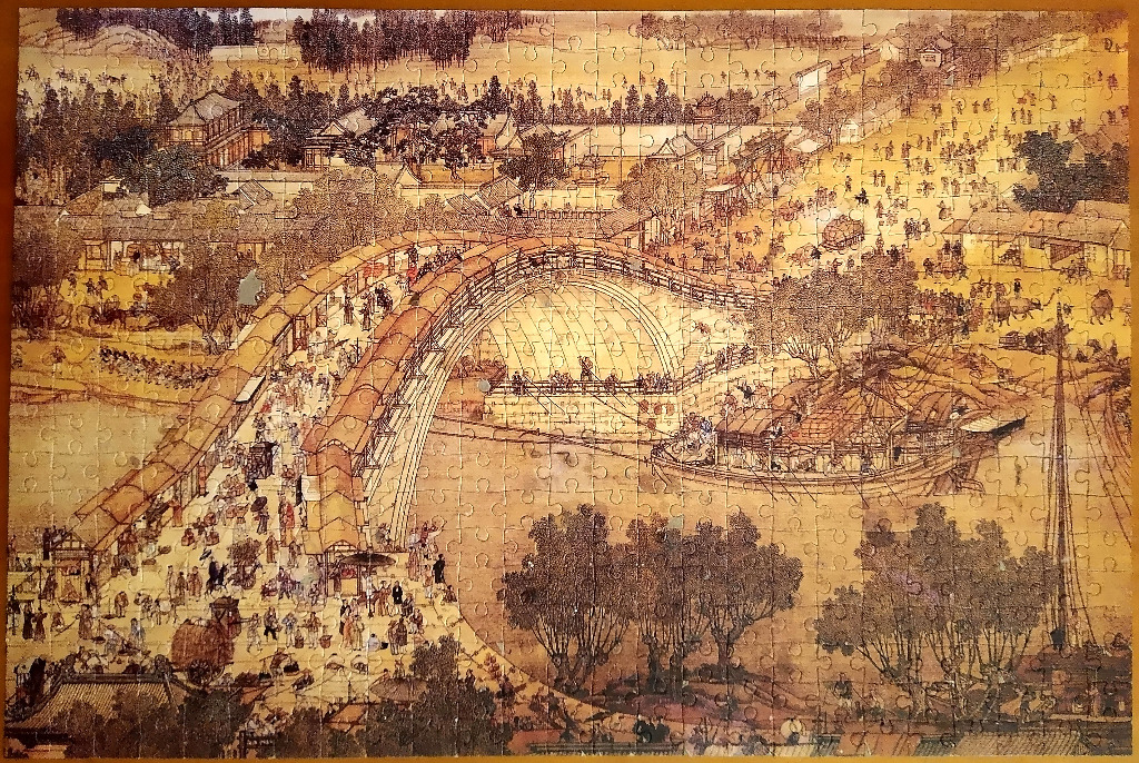 A detailed ink and wash painting depicting a bustling ancient Chinese riverside city with a large arched bridge.