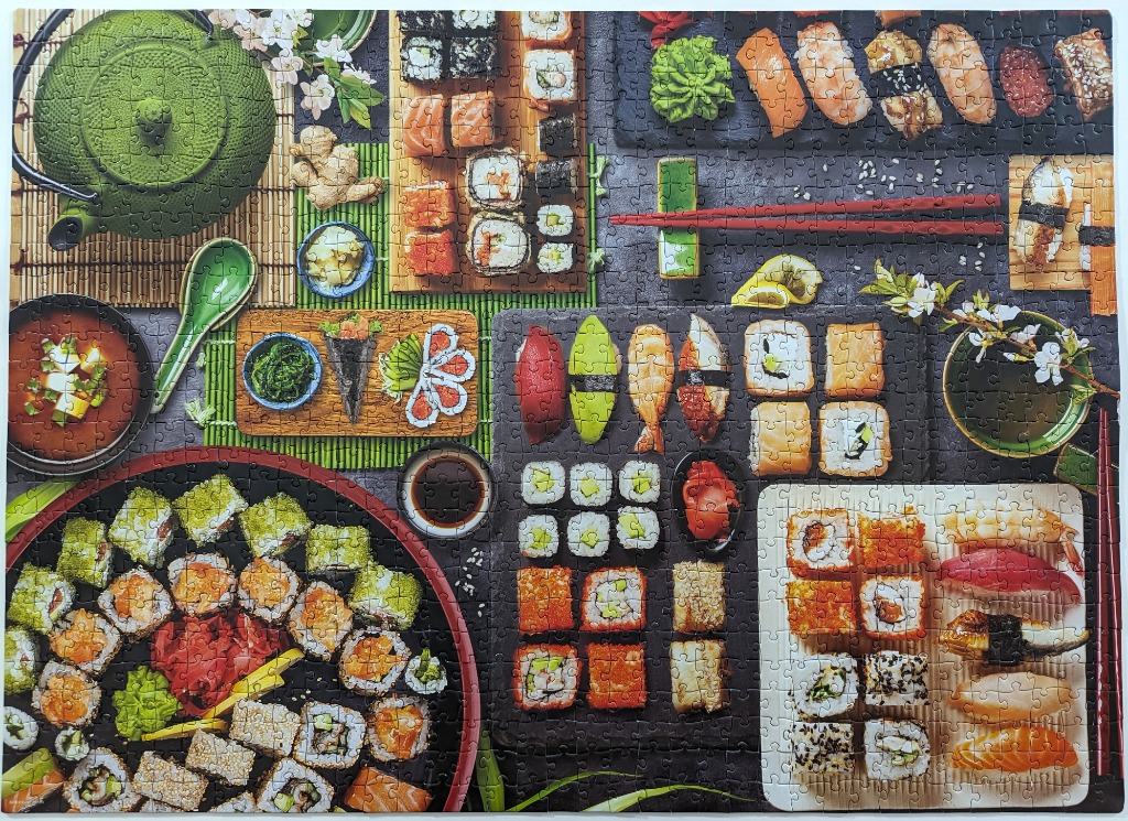 An overhead view of a sushi and Japanese cuisine spread with rolls, nigiri, and a teapot.