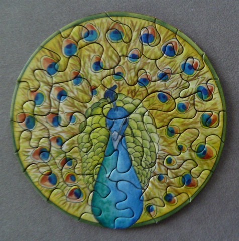 Circular illustration of a stylized peacock with a fanned tail of golden-yellow feathers and blue eyespots.
