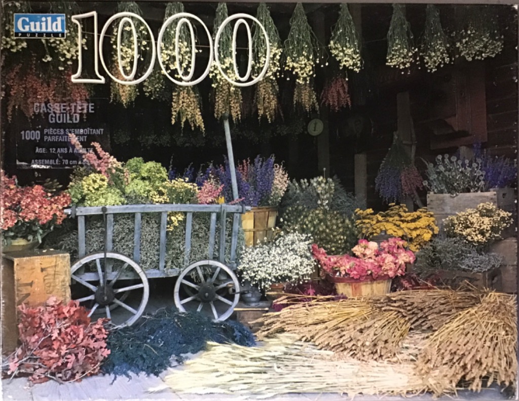 An old-fashioned wooden cart filled with colorful dried wildflowers and bundles of grass in a rustic setting.