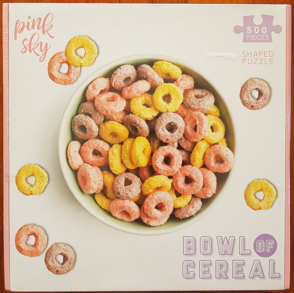 A bowl filled with colorful, ring-shaped breakfast cereal against a pale background.