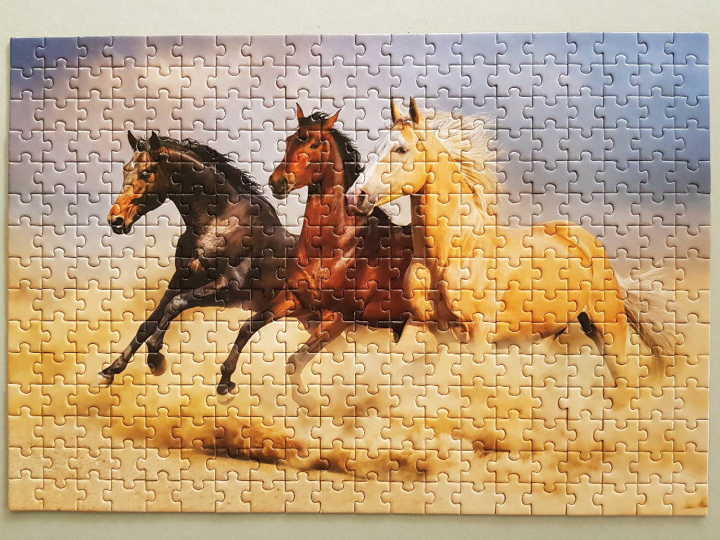 Three horses running across a dusty landscape against a gradient sky.