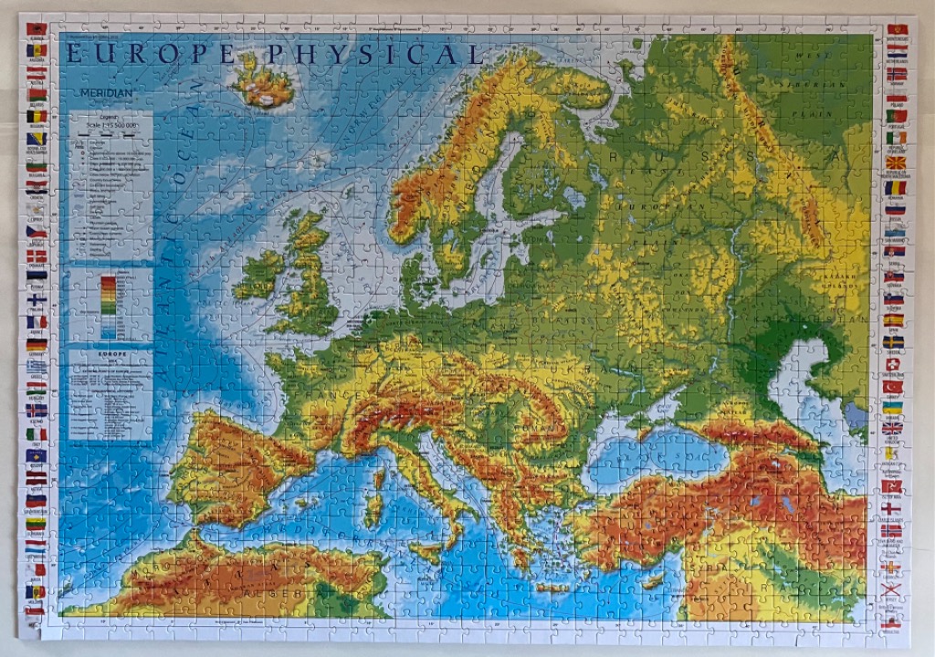 A physical map of Europe with colorful topographic terrain, national flags on the borders, and ocean depths.