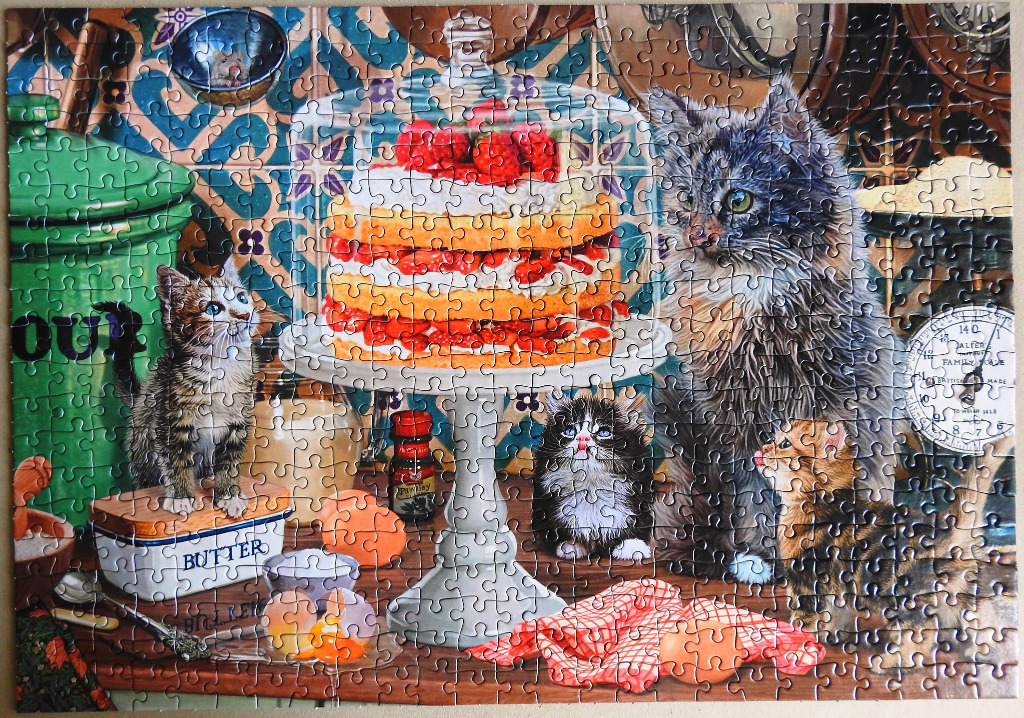 A kitchen scene with a tiered cake, kittens, and vintage baking supplies.