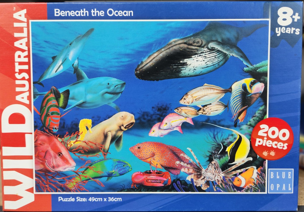 Underwater scene featuring a variety of marine life including a humpback whale, shark, sea cow, and tropical fish.