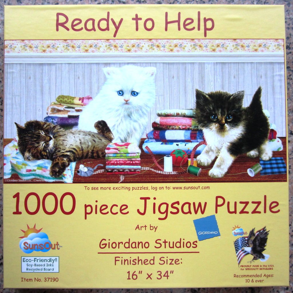 Three kittens sitting and lying among sewing supplies, fabrics, and quilts.