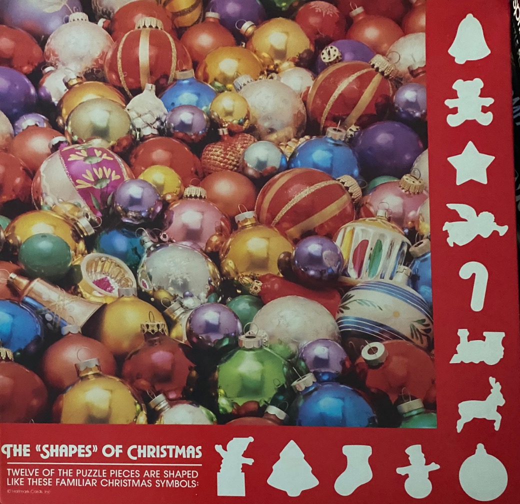 A dense pile of shiny, multi-colored Christmas ornament baubles in various sizes and textures.