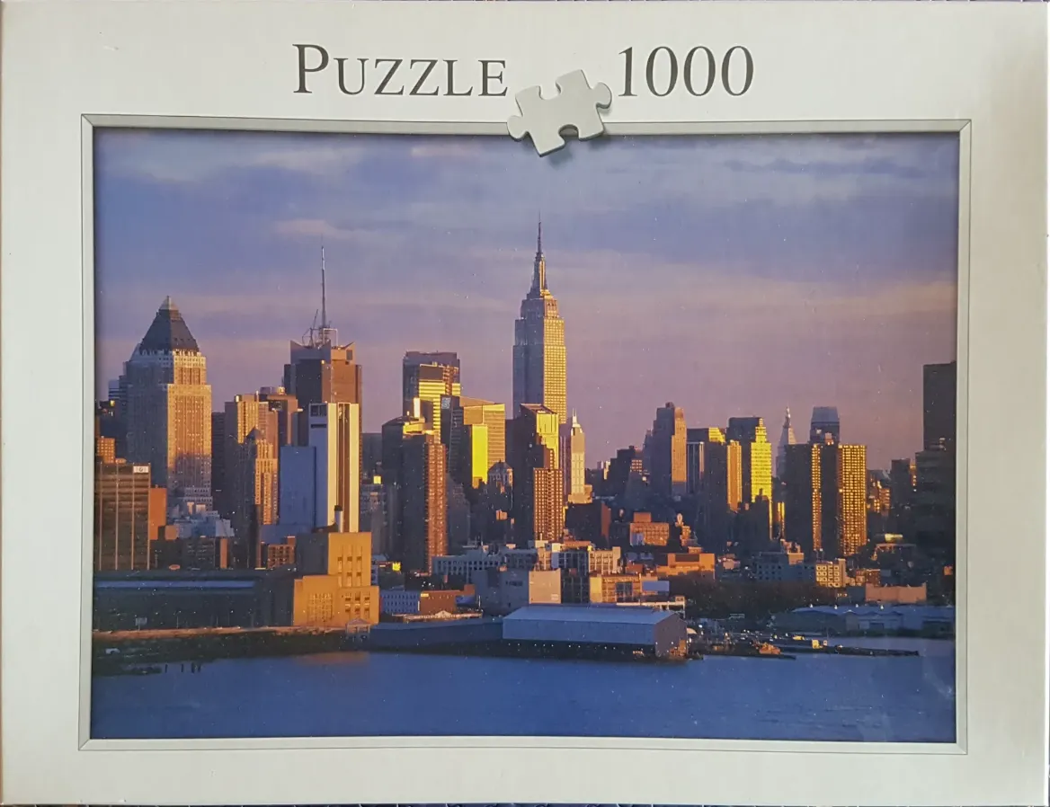 A panoramic photograph of the Manhattan skyline at sunset with the Empire State Building as the central focal point.