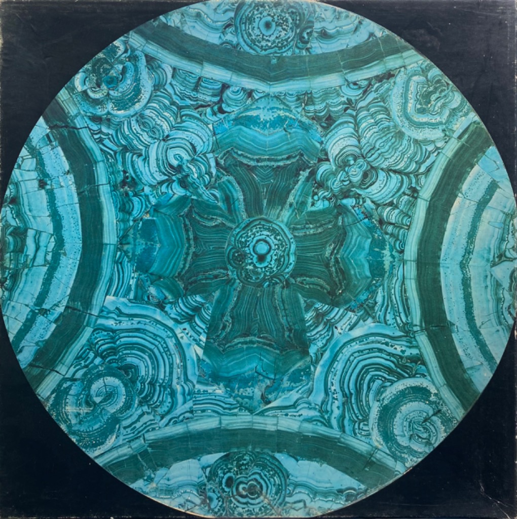 A circular pattern of green and turquoise malachite stone showing organic, concentric banding.