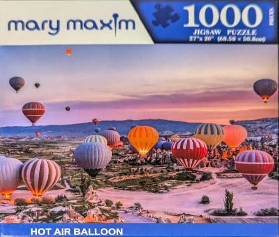 Numerous colorful hot air balloons floating over a rugged rocky landscape at sunrise.
