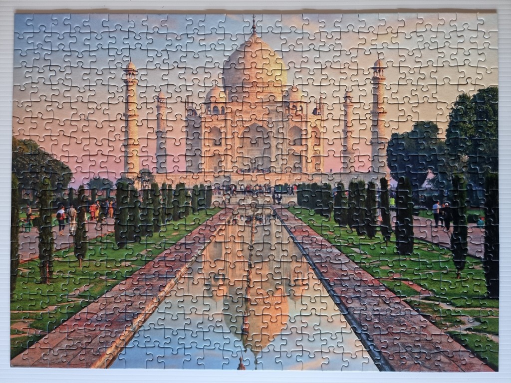 The Taj Mahal at sunset with its reflection in a long, rectangular garden pool.