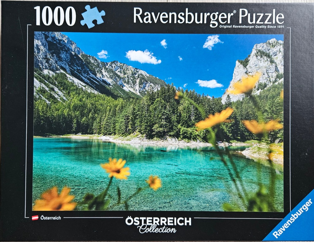 A scenic photograph of a crystal-clear turquoise mountain lake in Austria framed by yellow wildflowers in the foreground.