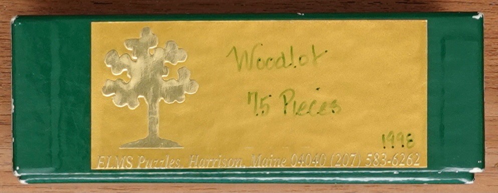 A rectangular label featuring a gold tree silhouette and the handwritten text Woodlot 75 Pieces on a dark green background.